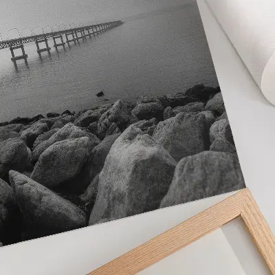 Poster paesaggio tranquillo con ponte e spiaggia rocciosa sotto un cielo grigio