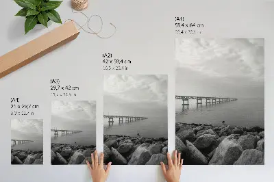 Poster paesaggio tranquillo con ponte e spiaggia rocciosa sotto un cielo grigio