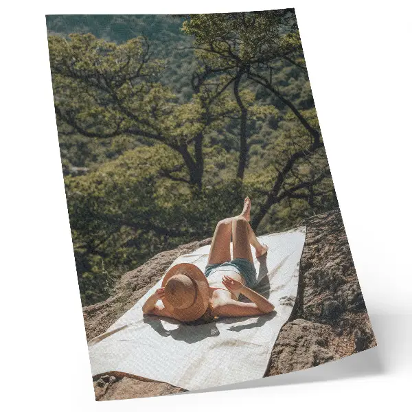 Foto su tela persona che si rilassa su una roccia in mezzo agli alberi verdi indossando un cappello