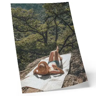 Foto su tela persona che si rilassa su una roccia in mezzo agli alberi verdi indossando un cappello