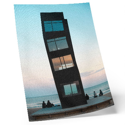 Poster Una moderna torre nera che si erge su un mare blu.