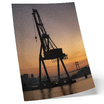 Poster silhouette di una gru industriale al tramonto su un ponte