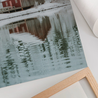 Poster Un cottage rosso tra alberi innevati in riva all'acqua