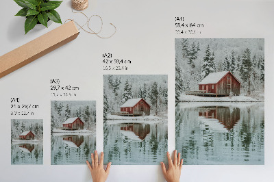 Poster Un cottage rosso tra alberi innevati in riva all'acqua